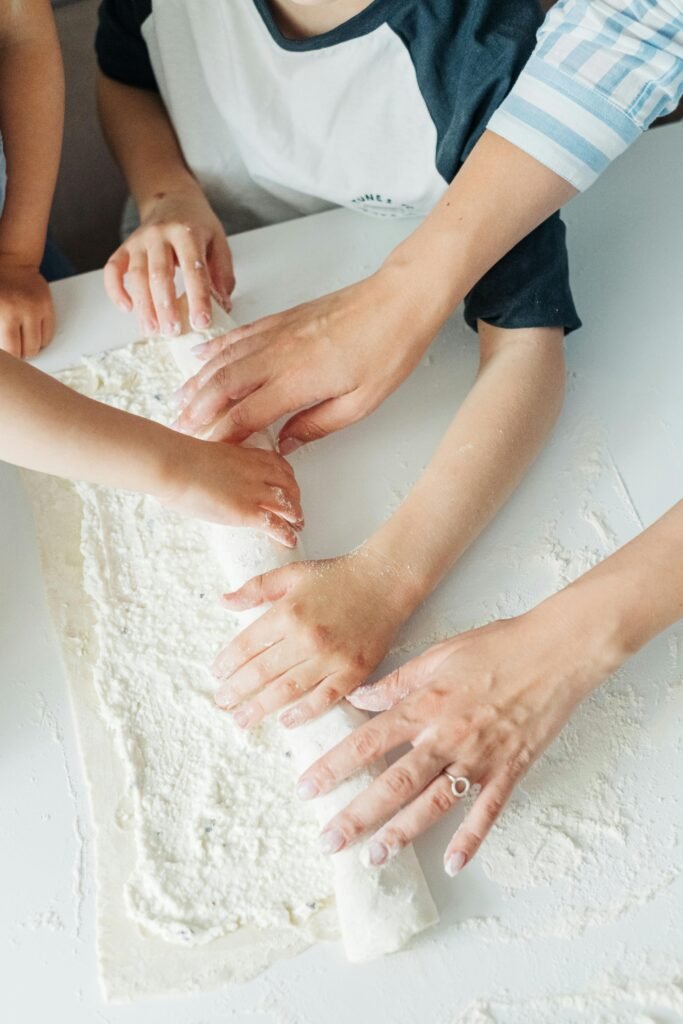 Family members collaborate joyfully in rolling dough, crafting cherished kitchen moments.